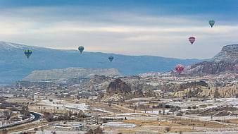 Hot Air Balloons Flying Over Snowy Cappadocia Landscape
