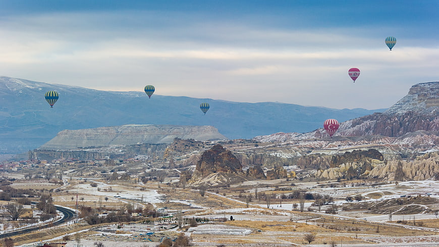 Hot Air Balloons Flying Over Snowy Cappadocia Landscape