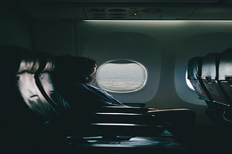 Woman Looking Out Airplane Window at Clouds