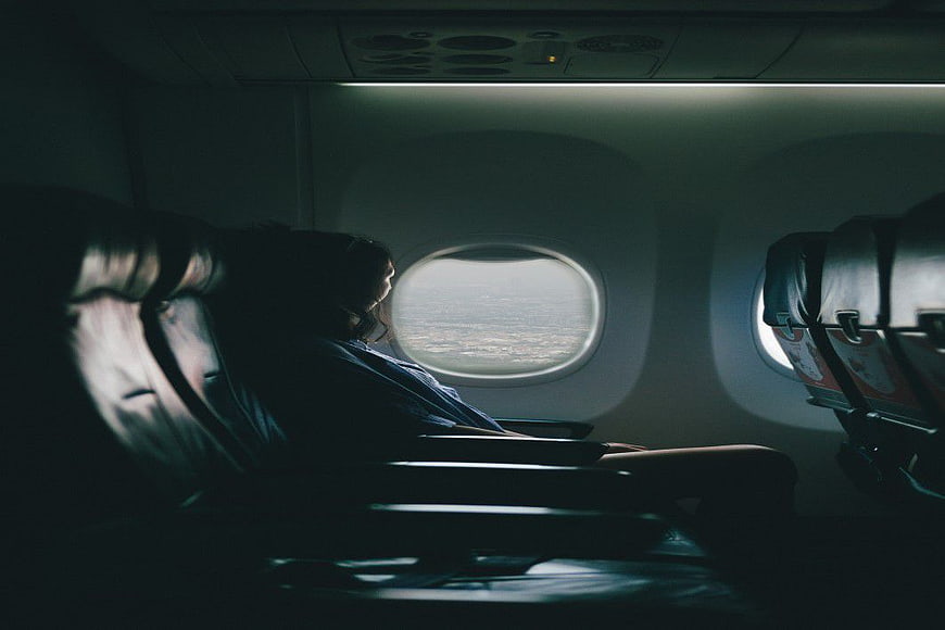 Woman Looking Out Airplane Window at Clouds