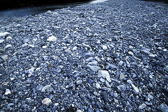 Blue gray pebbles on a riverbank in the Italian Alps