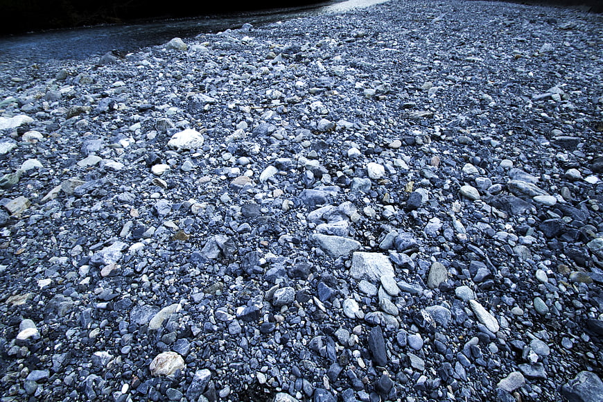 Blue gray pebbles on a riverbank in the Italian Alps