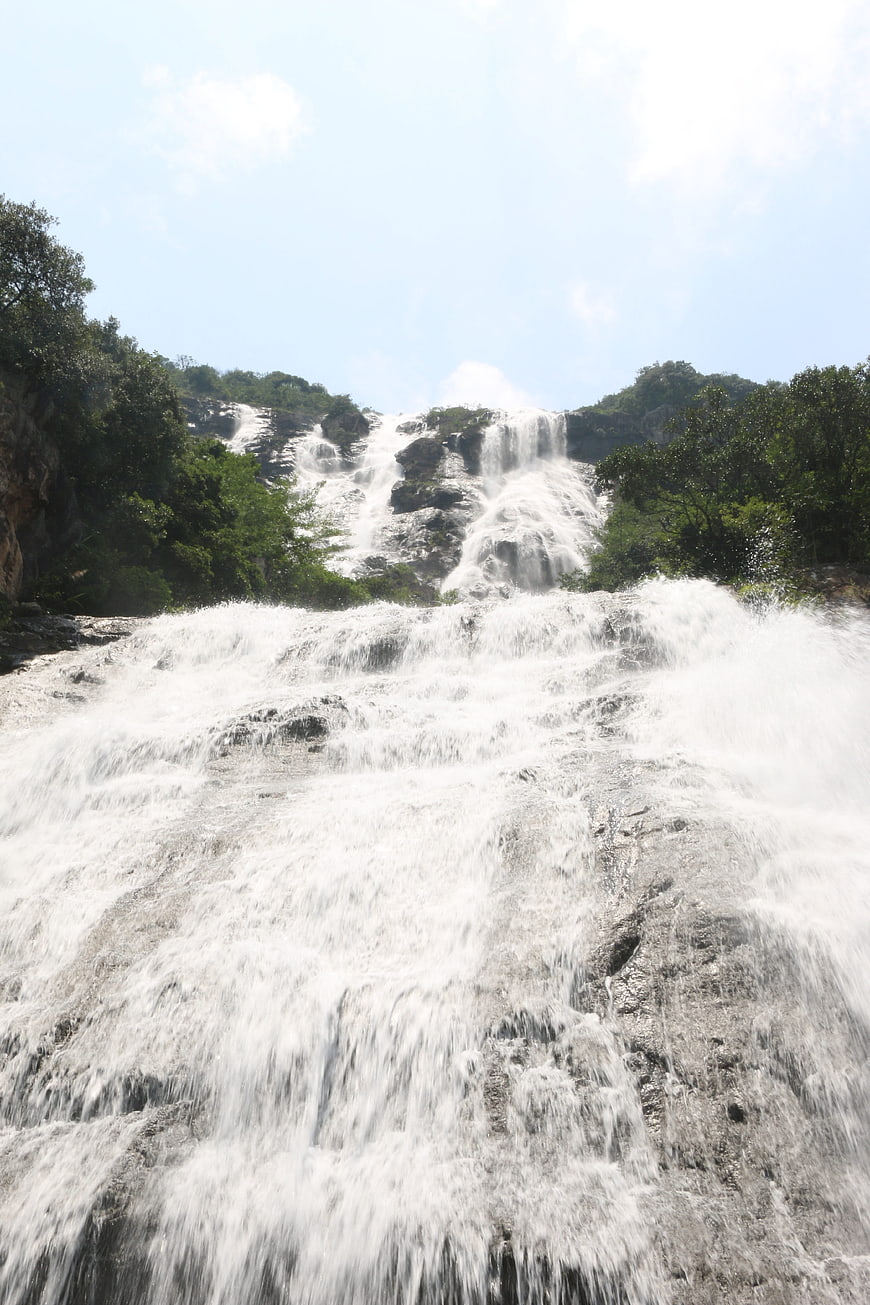 Wide cascading waterfall flowing over rocky terrain in nature