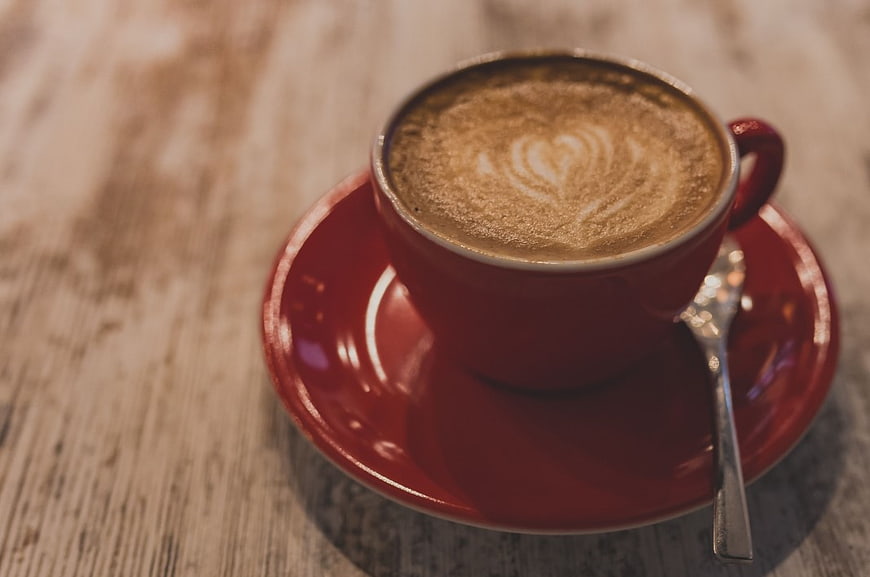 Red Cup Cappuccino with Heart Latte Art on Wooden Table