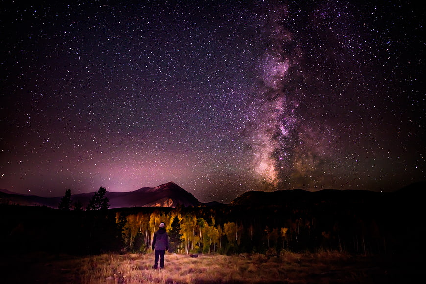 Man Standing Under Milky Way Galaxy in Mountain Landscape