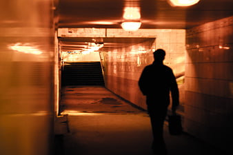 Silhouette of man walking in dimly lit underground tunnel