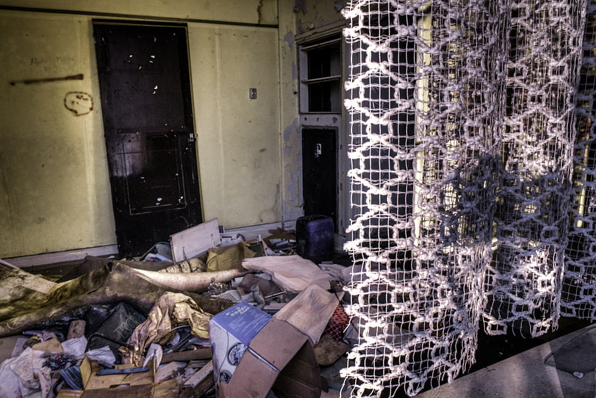 Abandoned room interior with debris and hanging netting