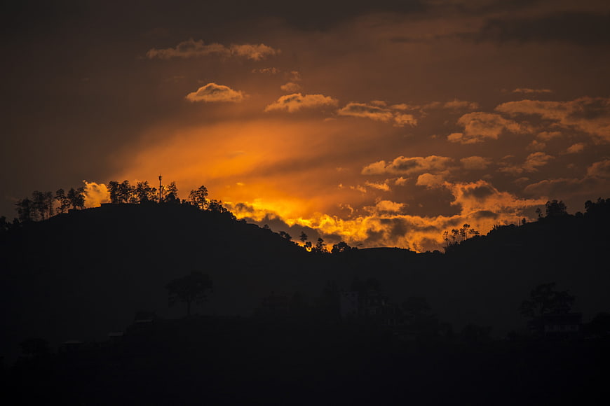 Dramatic Orange Sunset Over Silhouetted Hills And Clouds