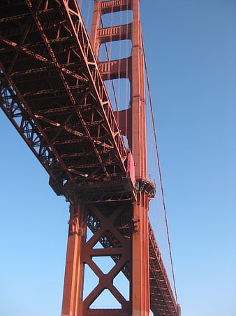 Low angle view of Golden Gate Bridge steel structure against blue sky