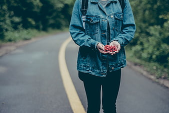 Person holding red berries on a country road