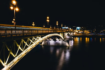 Illuminated Steel Bridge at Night with City Reflections