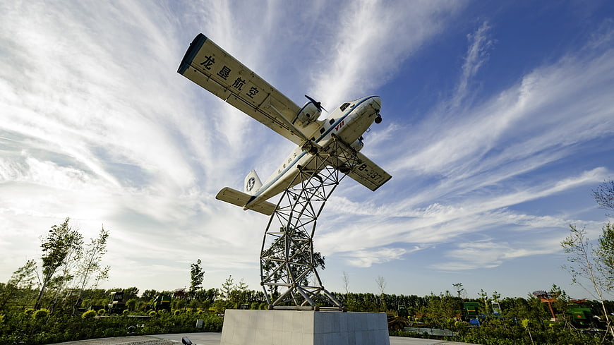 White airplane sculpture on metal stand against blue sky