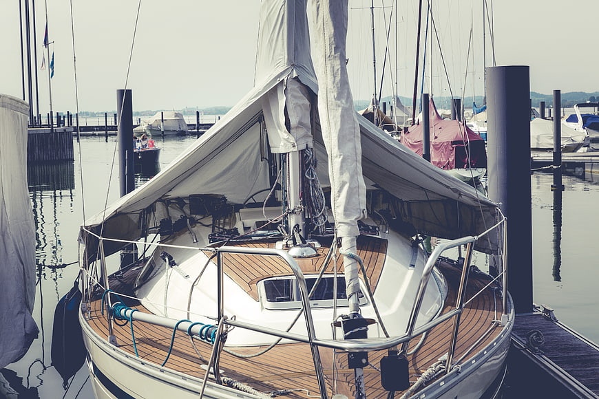 White sailboat docked at marina with wooden deck