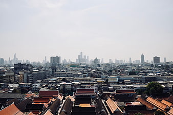Bangkok City Skyline View With Traditional Roofs And Hazy Horizon