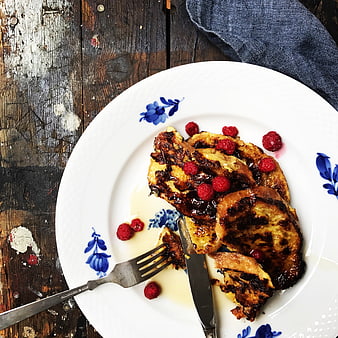 Overhead view of French toast with raspberries on rustic wood
