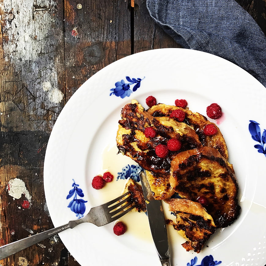 Overhead view of French toast with raspberries on rustic wood