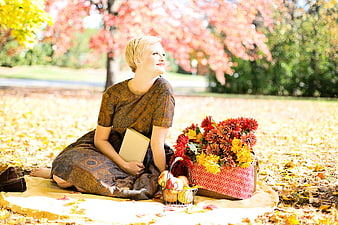 Woman reading book on autumn picnic blanket with flowers
