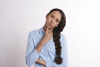Skeptical woman with braided hair thinking in blue shirt