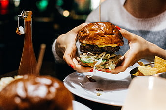 Woman holding juicy gourmet burger with chips