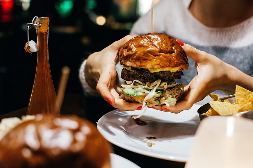 Woman holding juicy gourmet burger with chips