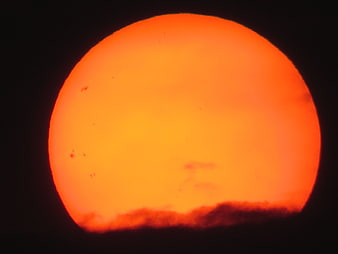 Close-up of the Sun with visible sunspots and dark clouds