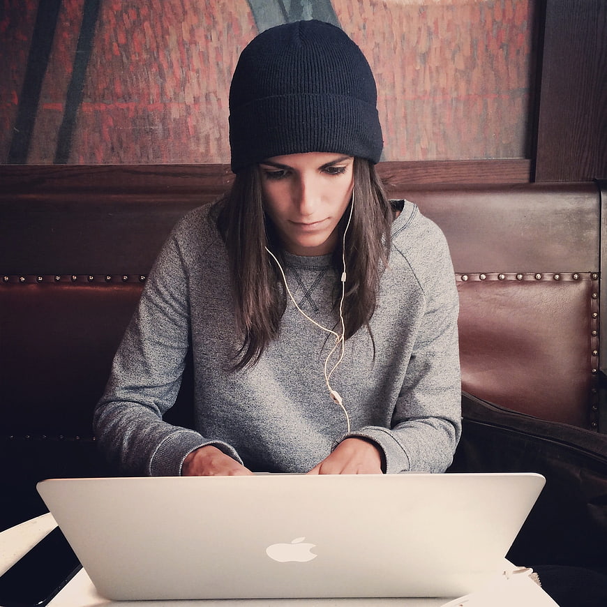 Woman in Beanie Working on Laptop in Cafe