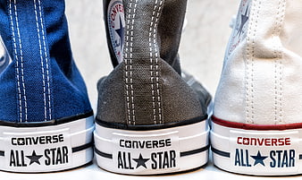 Close-up of three Converse All Star sneakers in blue, gray, and white