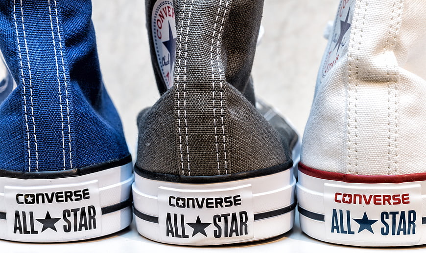 Close-up of three Converse All Star sneakers in blue, gray, and white