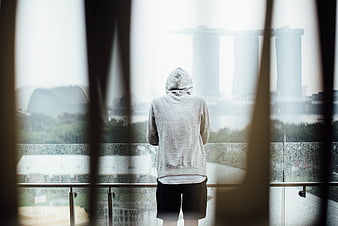 Man in Hoodie Looking at Rainy City Skyline