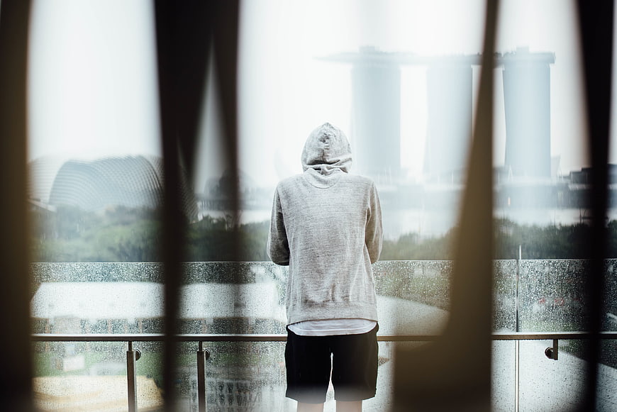 Man in Hoodie Looking at Rainy City Skyline