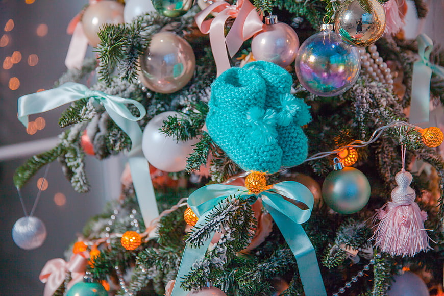 Close-up of knitted baby booties on a decorated Christmas tree