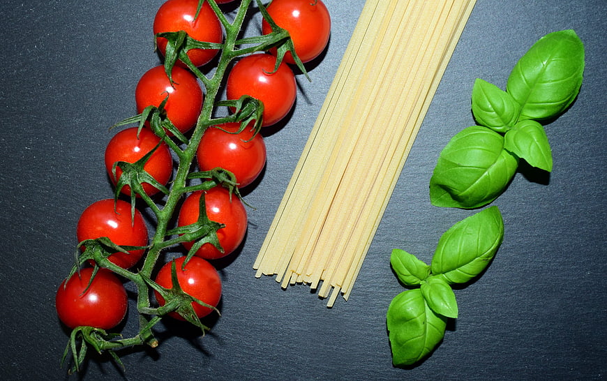 Cherry tomatoes, spaghetti, and basil arranged as Italian flag colors