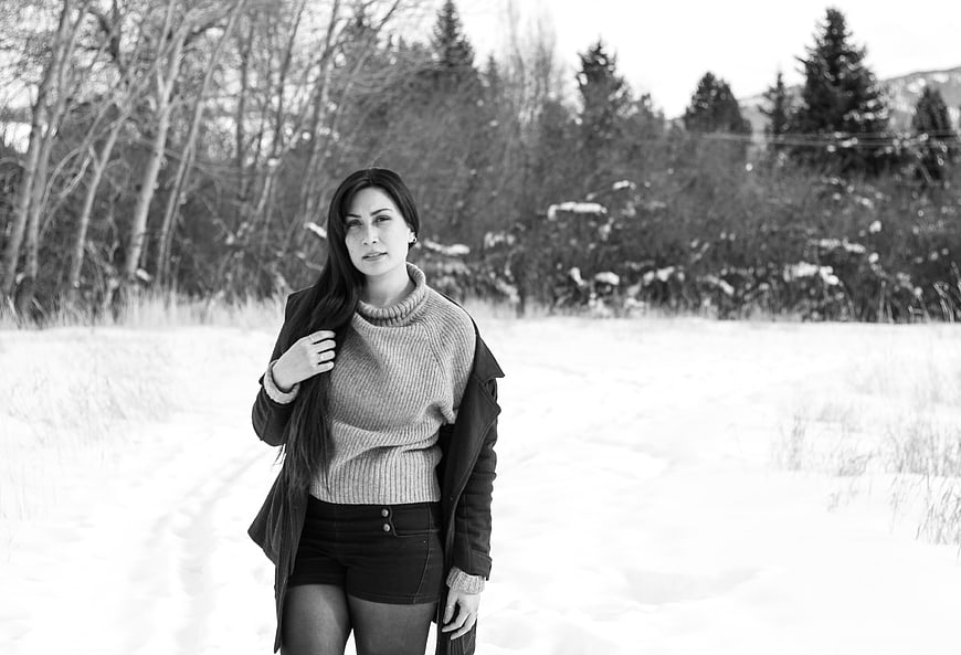 Woman in winter sweater standing in snowy forest path