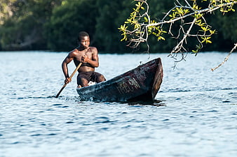 Young Man Rowing Wooden Boat on River
