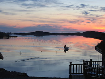 Silhouette of boat on calm water at sunset