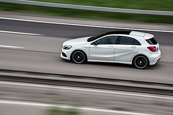 White hatchback car driving on highway with motion blur