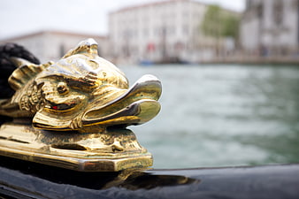 Close-up of ornate golden dolphin figurehead on a Venetian boat