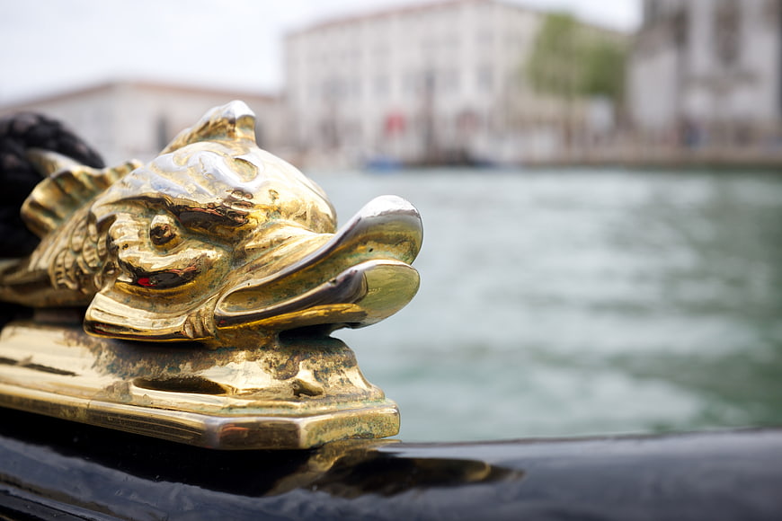 Close-up of ornate golden dolphin figurehead on a Venetian boat