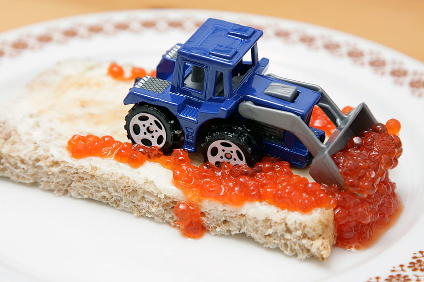 Toy excavator scooping red caviar on bread