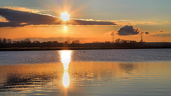 Golden Sunset Over Calm Lake with Cloud Reflections
