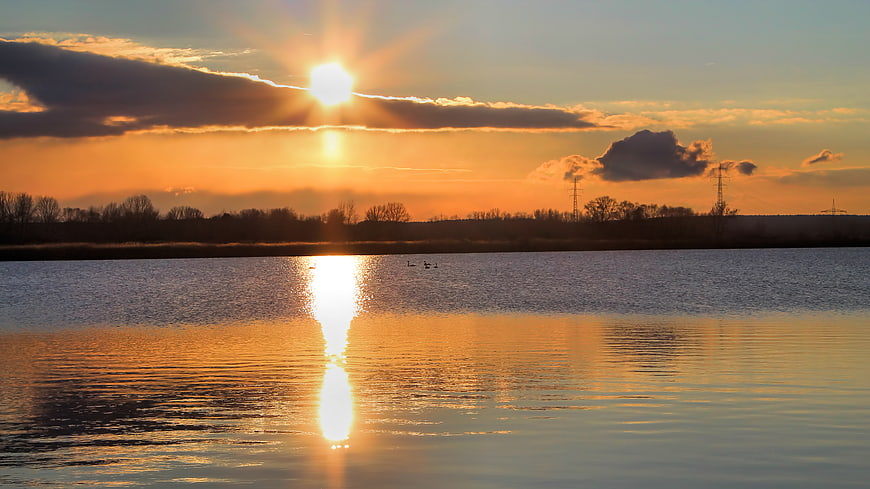 Golden Sunset Over Calm Lake with Cloud Reflections