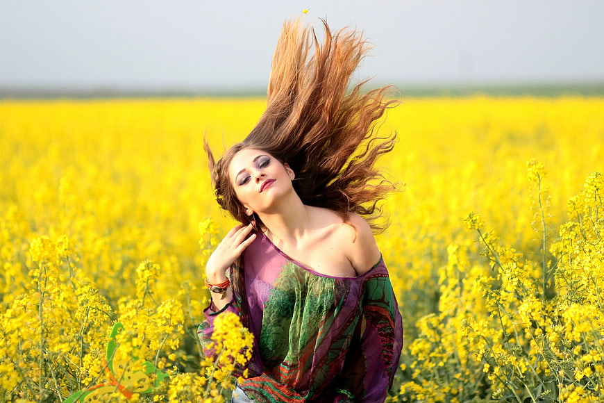 Young woman with flowing hair in yellow flower field
