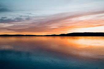 Serene Sunset Reflection on Frozen Lake with Silhouette Hills