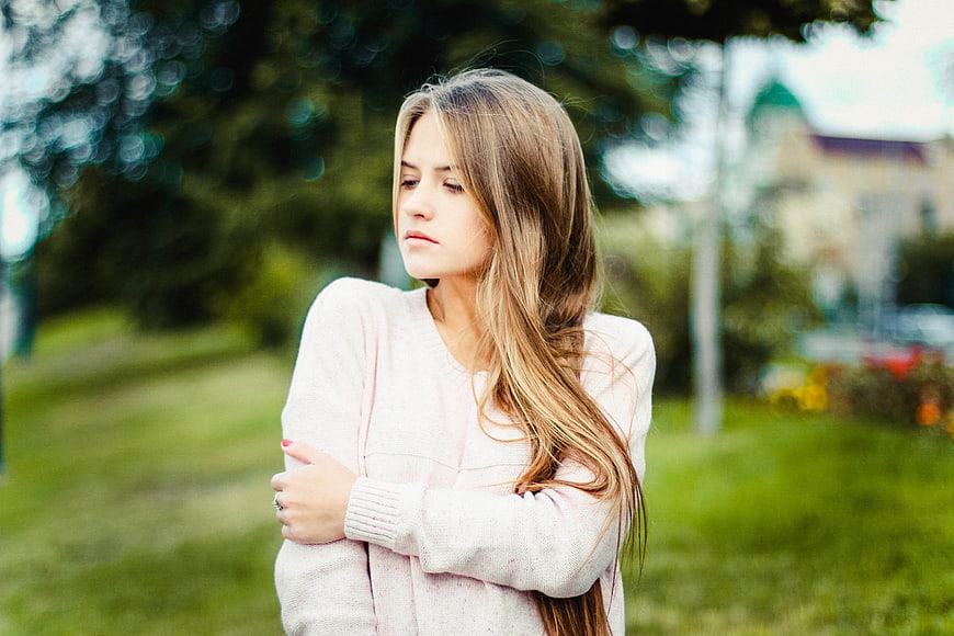 Young woman with long hair in pink sweater outdoors