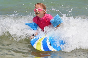Young Girl Surfing on Bodyboard in Ocean Waves