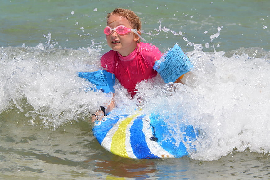 Young Girl Surfing on Bodyboard in Ocean Waves