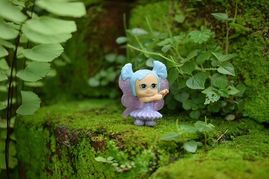 Cute purple fairy figurine on mossy forest floor