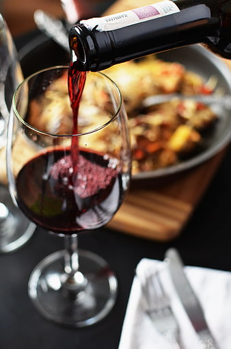 Pouring Red Wine into Glass with Dinner Background
