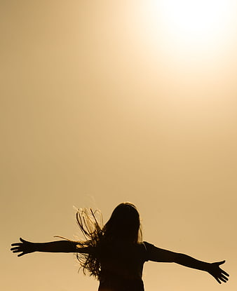 Silhouette of Woman with Arms Outstretched Against Golden Sky