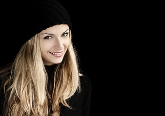 Smiling Blonde Woman in Black Beanie on Black Background